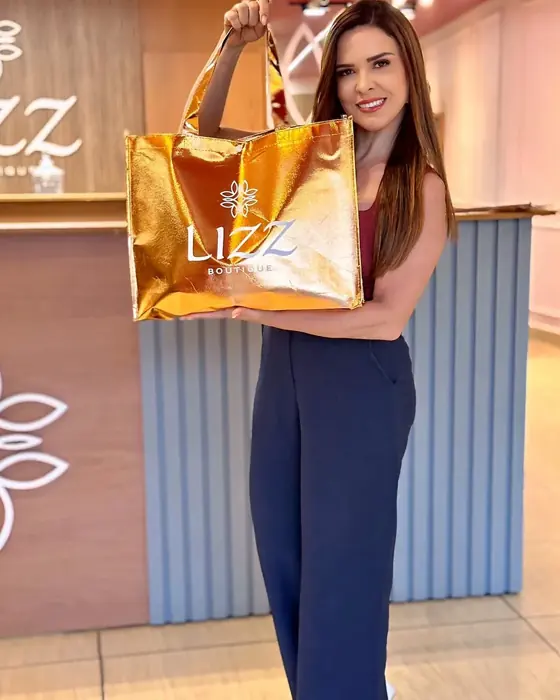 Viviane, dona da Lizz Boutique, dentro da loja com a sacola da Lizz